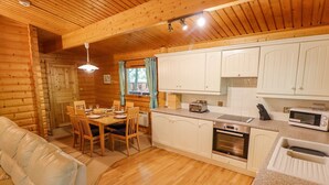 A cozy log cabin interior with a dining area, kitchen, and a sofa. - Bamboo Retreat (Louth)