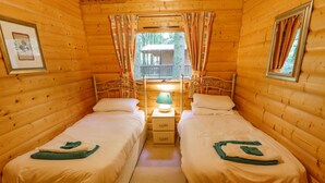 A cozy cabin room with two beds, a nightstand, and a window with curtains. - Bamboo Retreat (Louth)