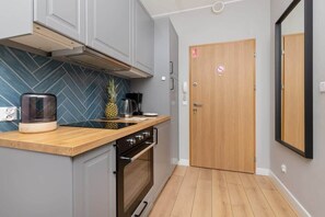 A compact kitchen with a wooden countertop, a built-in oven, and a herringbone tile backsplash.
