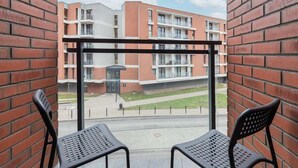 A balcony with two chairs, a view of a multi-story building with balconies, and a clear sky. - Modern Studio in the Center | Balcony and Workspace (Gdańsk)