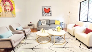 A modern living room with two sofas, a coffee table, and a painting on the wall.