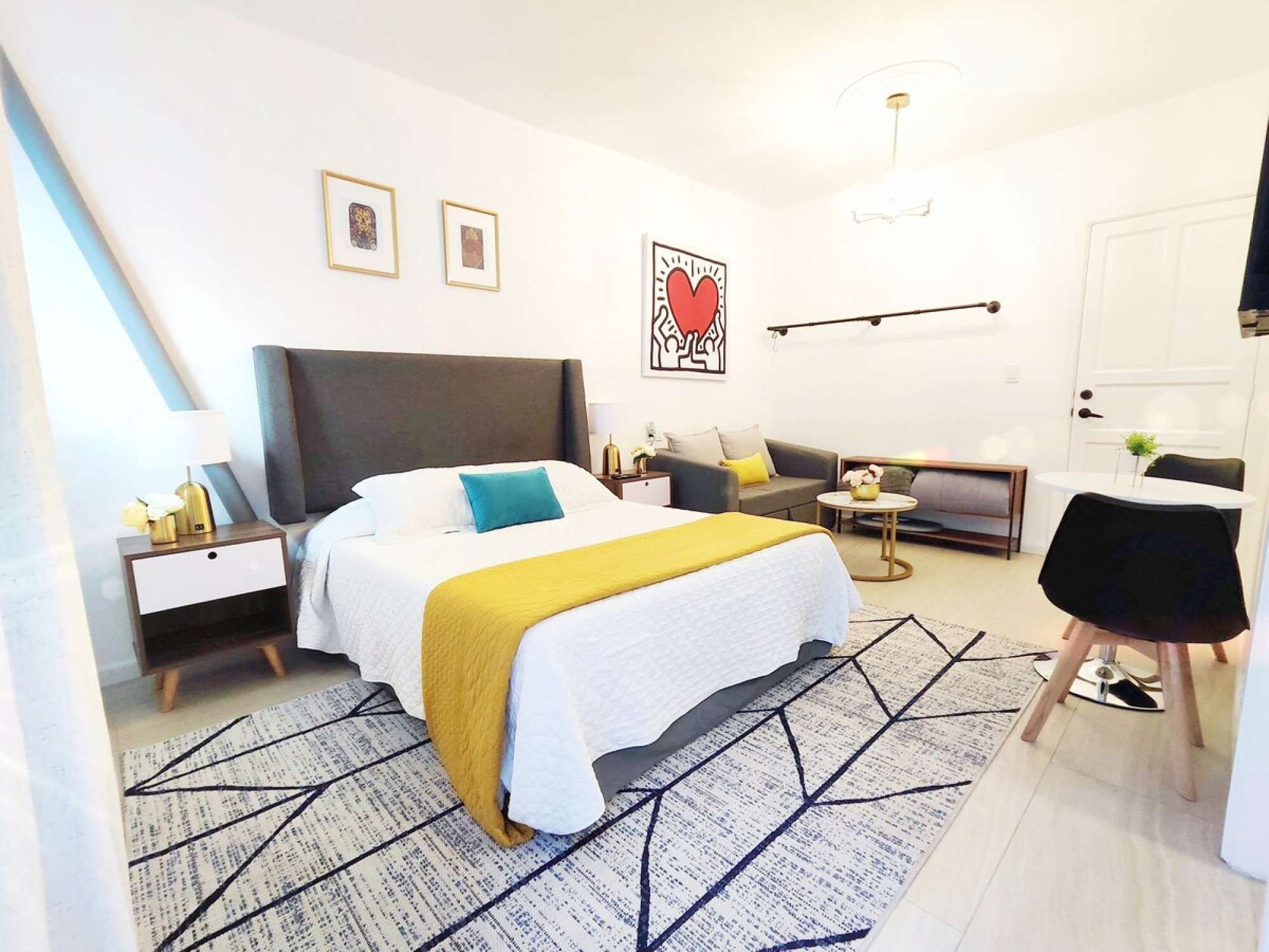 Een moderne slaapkamer met een groot bed, nachtkastjes, een bank, een bureau en een stoel.