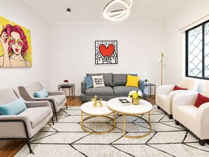 A modern living room with a grey sofa, a white sofa, and a coffee table with a book and flowers.