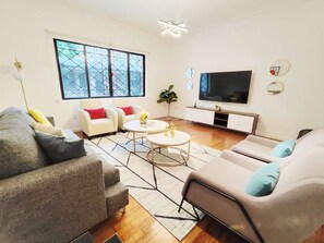 Un salon moderne comprenant un canapé, une table basse, un téléviseur et une grande fenêtre offrant une belle vue.