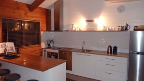 Et moderne køkken med hvide skabe, et rustfrit stål køleskab og en træø med barstole.