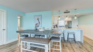 Une cuisine moderne dotée d’un îlot central, de meubles blancs et d’un coin repas avec une banquette et des chaises.