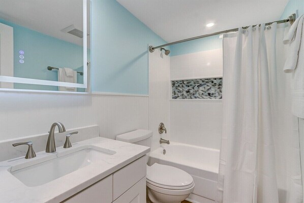 A bathroom with a white sink, two faucets, a toilet, and a bathtub.