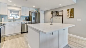 A modern kitchen with white cabinetry, stainless steel appliances, and a large island. - Sunrise View | Oceanfront Condo Amelia South D6 on Amelia Island! (Fernandina Beach)