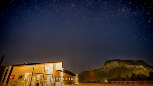 A modern building with a large glass facade, a flat roof, and a mountain in the background.