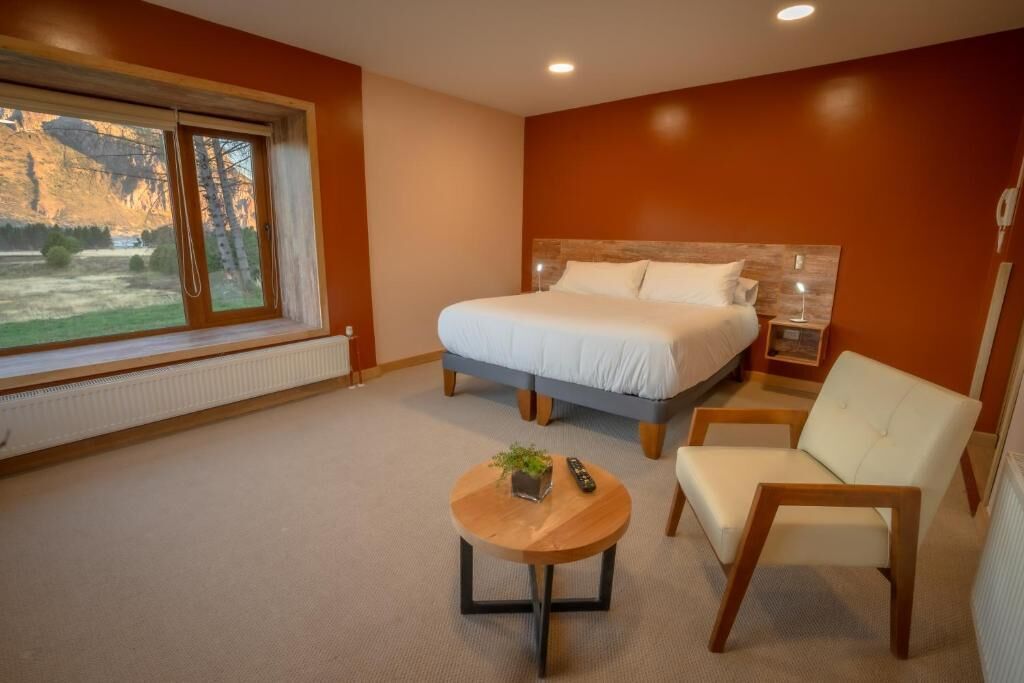 Ein Schlafzimmer mit Bett, Stuhl, Nachttisch und Fenster mit Landschaftsblick.