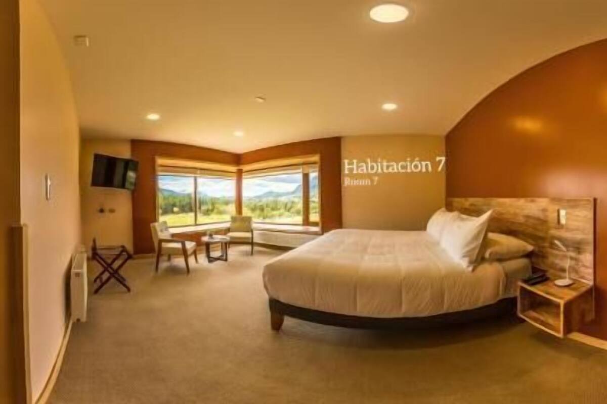 Ein Schlafzimmer mit Bett, Schreibtisch und Stuhl. Ein Fenster bietet Blick ins Freie.