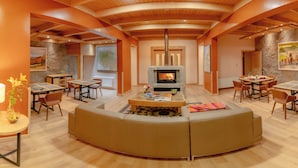 A modern living room with a fireplace, wooden ceiling beams, and a stone accent wall.