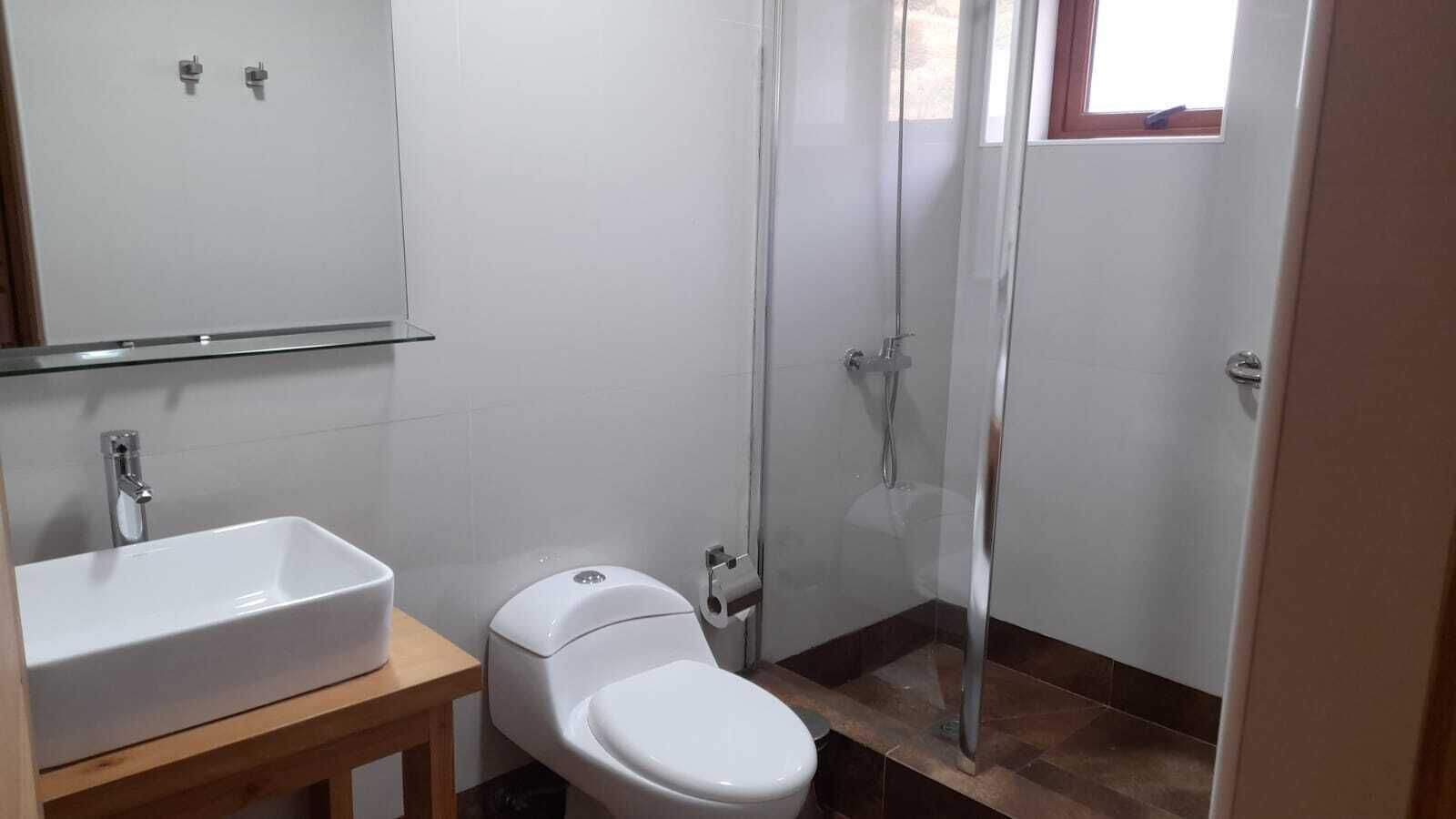 A bathroom with a white sink, toilet, and glass-enclosed shower.