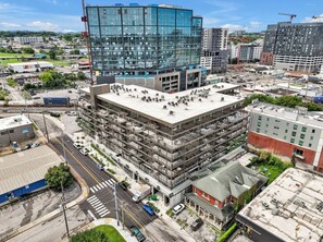 A multi-story building with a rooftop terrace, surrounded by other buildings and a busy street. - Honky Tonk Hideaway, Walk to Broadway! Gym, Pool, Parking (Nashville)
