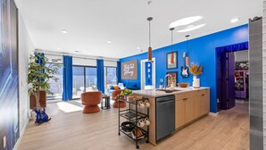 Une cuisine moderne avec un mur d’accent bleu, des armoires en bois et un îlot central doté d’un évier et d’un égouttoir.