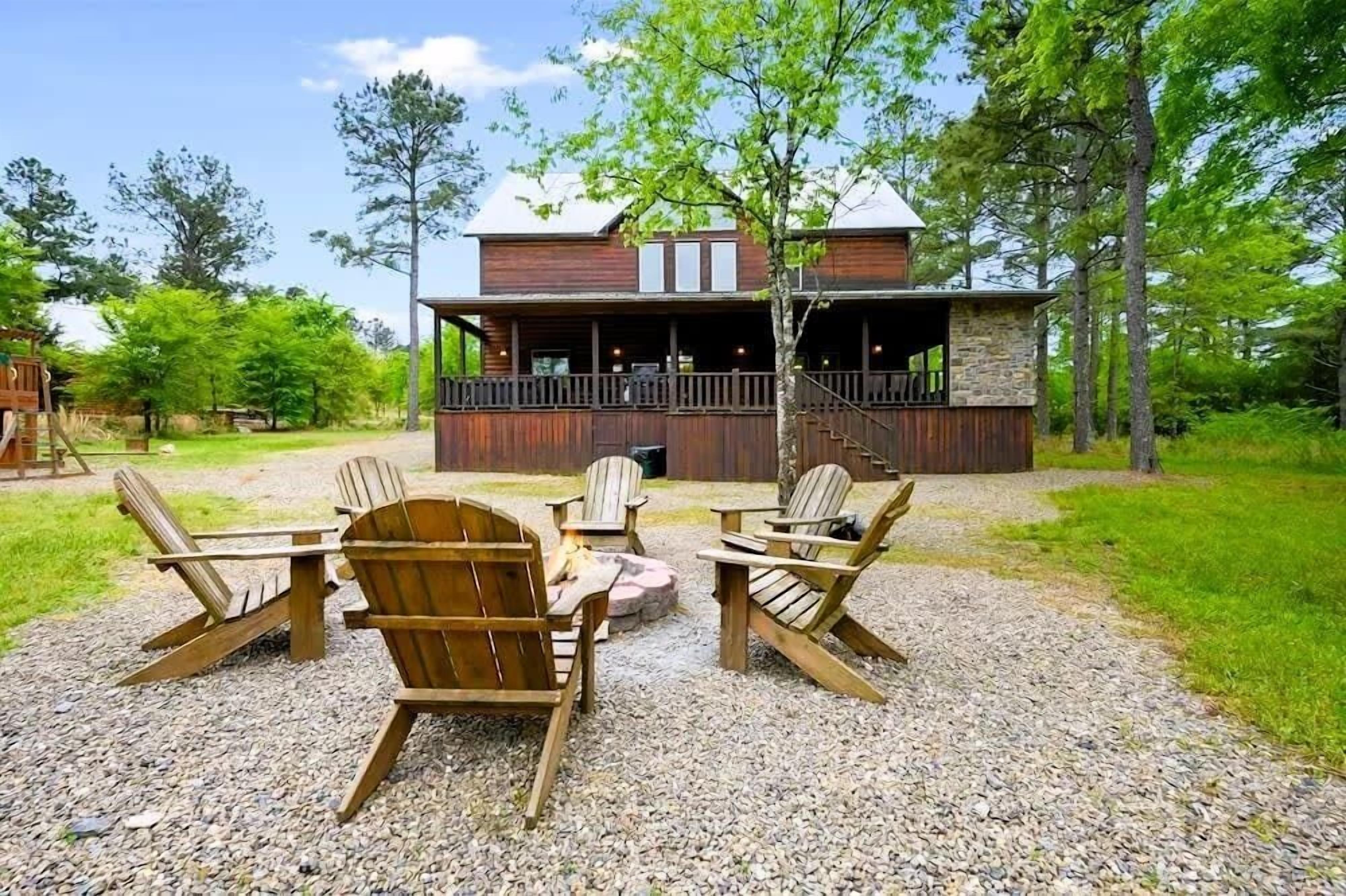 A wooden cabin with a stone exterior, a deck, and a fire pit.