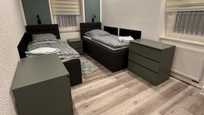Un dormitorio moderno con dos camas, un aparador y un escritorio.
