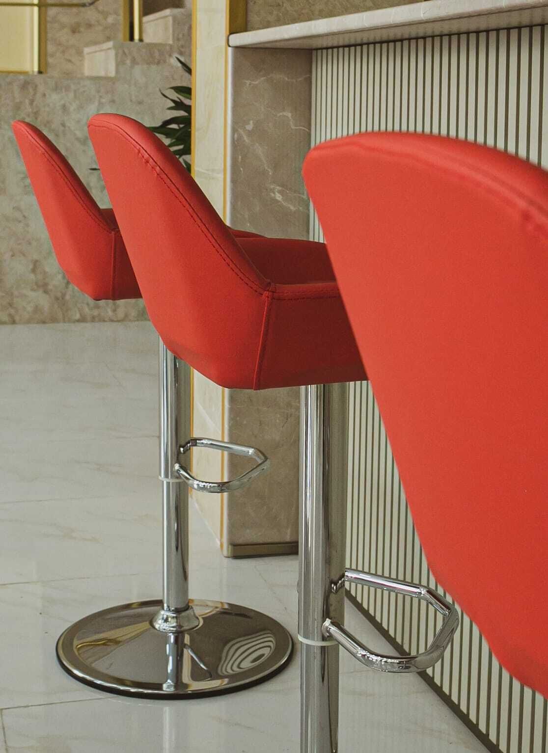 A modern bar area with red barstools and a chrome bar counter.