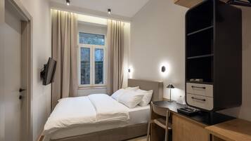 Un dormitorio moderno con cama, mesita de noche, escritorio y armario.