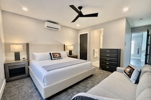 A modern hotel room with a large bed, bedside tables with lamps, a ceiling fan, and a dresser. - Exclusive Retreats Desert Vista: Luxury 6 Bedroom Retreat- Heated Pool/ Hot tub (Moab)