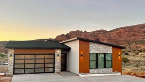 Uma casa moderna de dois andares com garagem, fachada de pedra e grandes janelas.