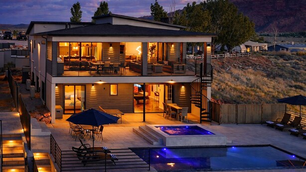 Uma casa moderna de dois andares com um pátio, área de estar ao ar livre e uma piscina.