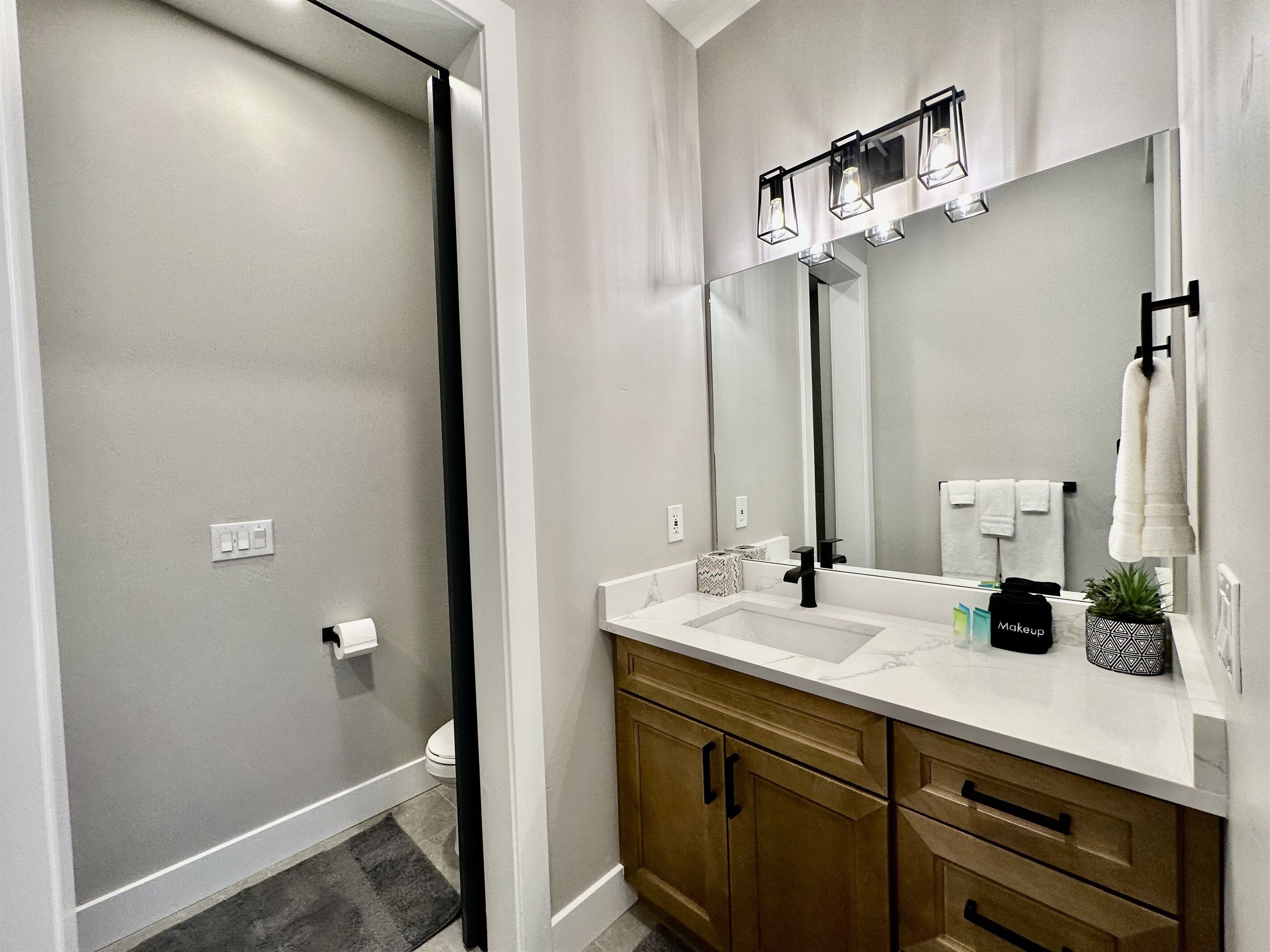 Un baño moderno con un espejo grande, un lavabo y una zona de ducha.