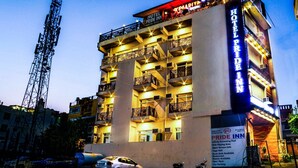 A hotel with multiple floors, balconies, and a sign indicating amenities like an infinity swimming pool, kids' play area, open terrace, yoga hall, and a bunk beds cafe. - HOTEL VINSOBER PRIDE INN (Narendranagar)