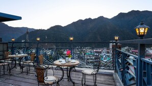 A terrace with tables and chairs, overlooking a mountainous landscape. - HOTEL VINSOBER PRIDE INN (Narendranagar)