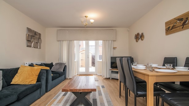 Una sala de estar moderna con un sofá, una mesa de comedor y un televisor.