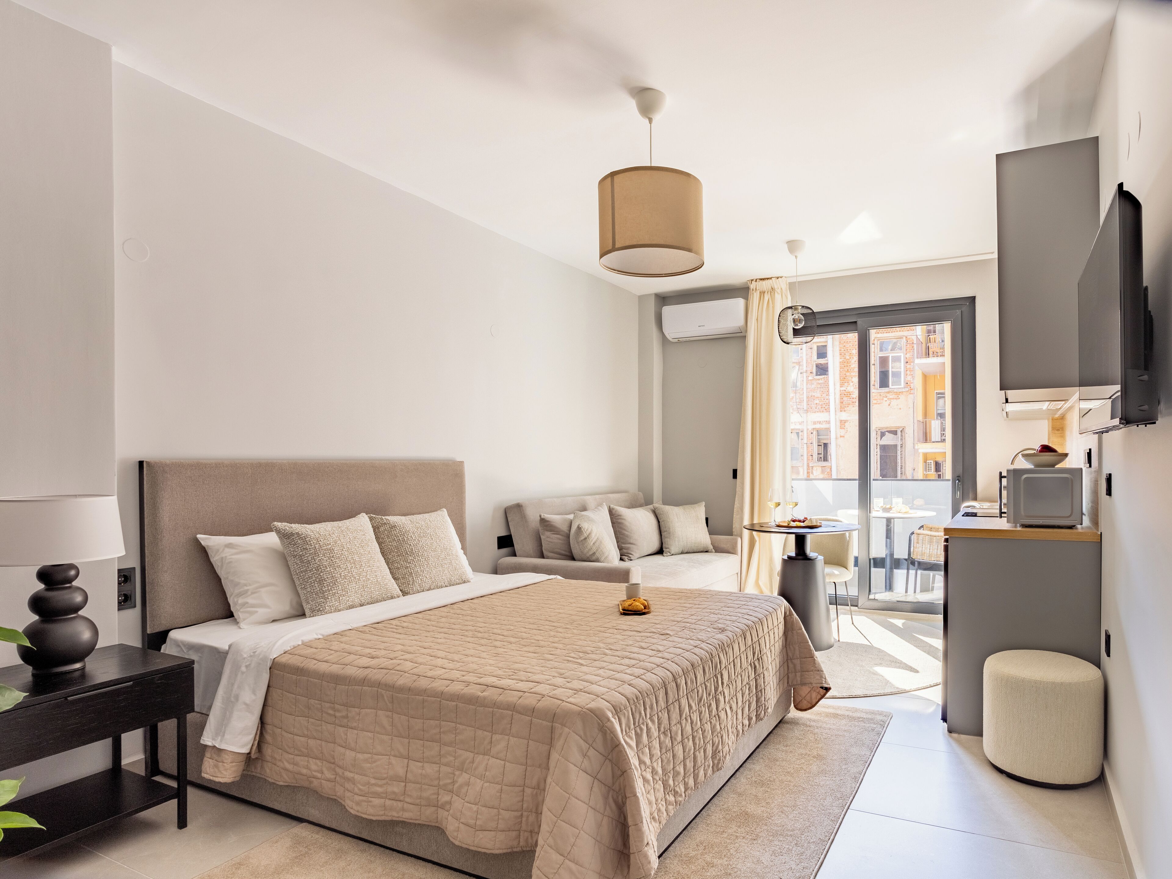Een moderne hotelkamer met een groot bed, een kleine zithoek, een eethoek en een televisie.