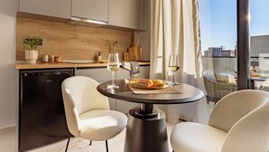 Una cocina moderna con lavavajillas, una mesa de comedor con sillas y vistas a la ciudad a través de amplios ventanales.