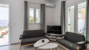 Un salon moderne avec deux canapés gris, une table basse blanche et un téléviseur à écran plat.