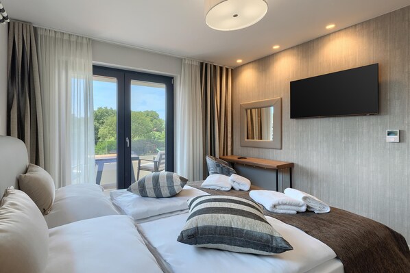 Una habitación de hotel moderna con una cama grande, un televisor de pantalla plana y vistas al exterior.