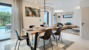 A modern dining area with a wooden table, black chairs, and a contemporary light fixture.