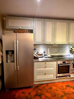 Eine Küche mit Kühlschrank, Backofen und Schränken.