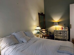 Une chambre à coucher comprenant un lit, une table de chevet, une commode, un miroir et une lampe.