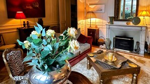 Ett vardagsrum med en soffa, ett soffbord, en öppen spis och en stor spegel.