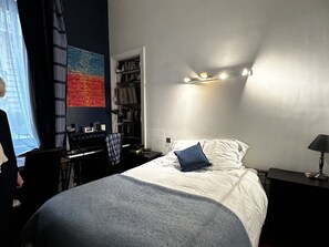 Ein Schlafzimmer mit Bett, Nachttischlampe und Schreibtisch mit Stuhl.