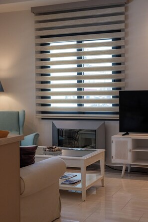 Un salon moderne avec un canapé, une table basse, un téléviseur à écran plat et une cheminée.