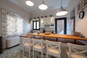 Cozinha moderna com armários brancos, bancada de madeira e iluminação pendente.