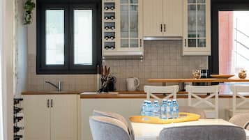 Une cuisine moderne avec des meubles blancs, un plan de travail en granit et un coin repas doté de chaises grises.