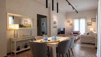 Une chambre d’hôtel comprenant un coin repas, un salon et une grande fenêtre avec des rideaux.