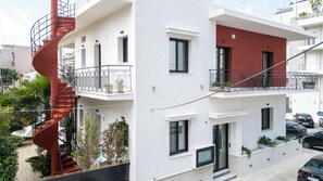 A modern two-story building with balconies, a spiral staircase, and potted plants.