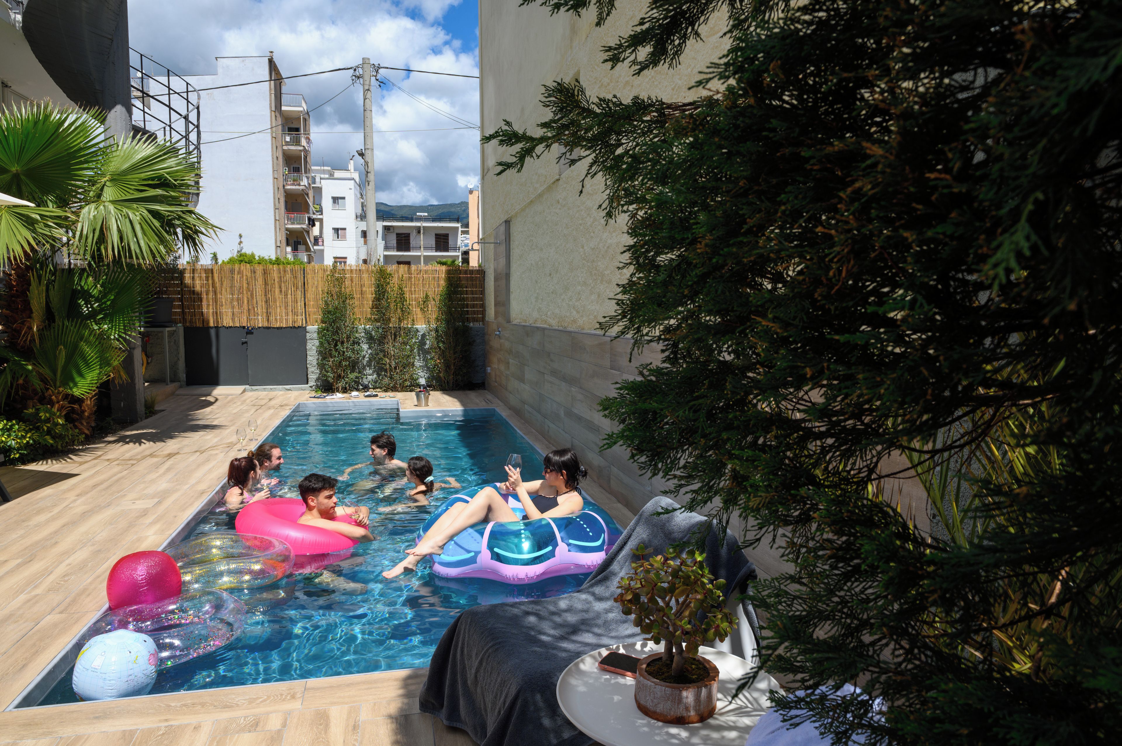 Ein Schwimmbecken mit Schwimmreifen, einem Blumentopf und einer gefliesten Liegefläche.
