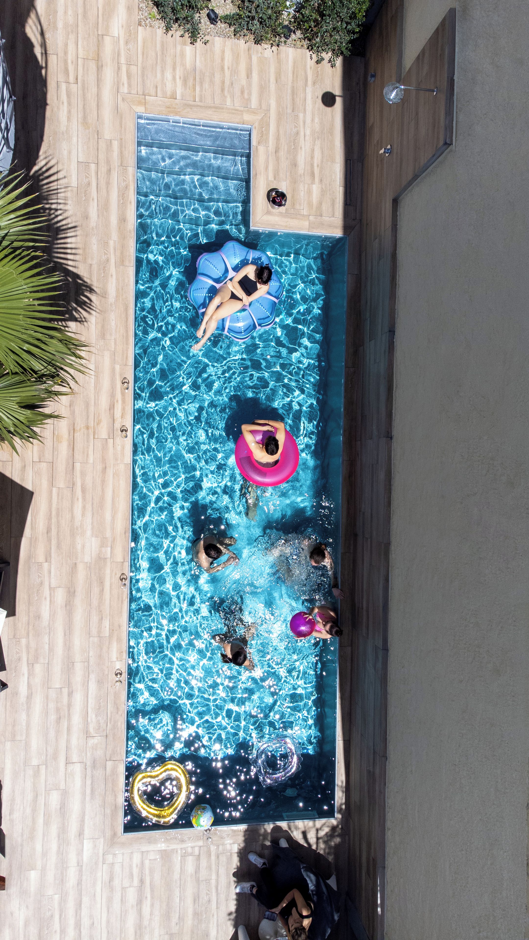 A rectangular swimming pool with clear blue water, surrounded by wooden deck flooring.