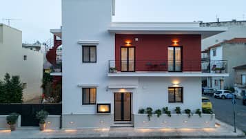 Un bâtiment moderne à deux étages, doté d’un balcon, d’une porte et de plantes en pot.
