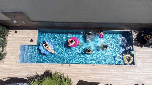Une piscine rectangulaire entourée d’une terrasse en bois.