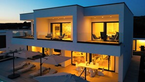Un bâtiment moderne à deux étages, doté de balcons, d’un espace extérieur aménagé pour s’asseoir et d’un intérieur bien éclairé.