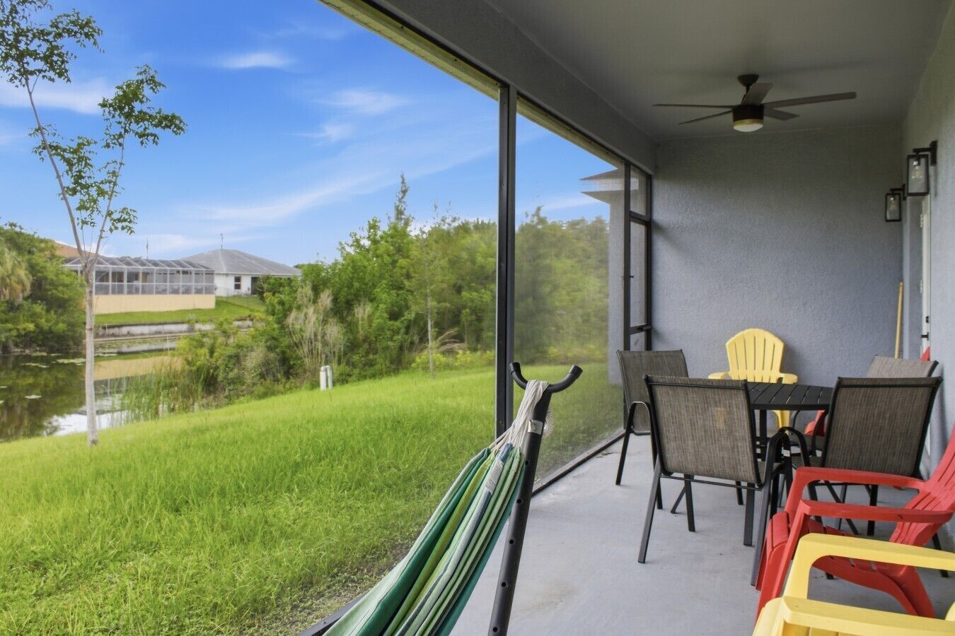 A balcony with a table and chairs, overlooking a grassy area and a building.